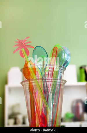 Bunte Plastiklöffel und kunststoffspachtel Werkzeug Küchenutensilien für Eis in Glas. Farbe der Strohhalm. Stapel Kunststoff farbig cocktail Strohhalme. Stockfoto