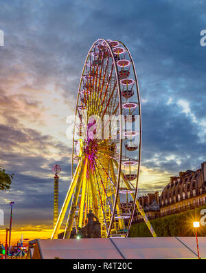 Die beliebten Symbol Riesenrad in Paris Frankreichs bei Sonnenuntergang in der Nähe von Louvre Museum mit historischen Gebäude im Hintergrund. Vertikale erschossen. Stockfoto