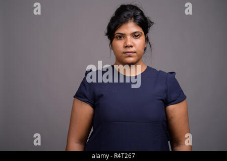 Junge Übergewicht schönen indischen Frau gegen grauer Hintergrund Stockfoto