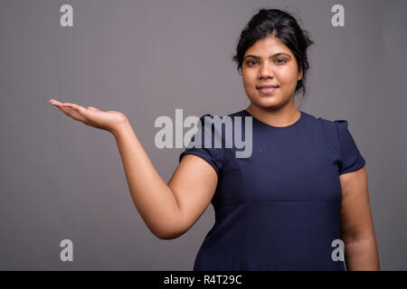 Junge Übergewicht schönen indischen Frau gegen grauer Hintergrund Stockfoto