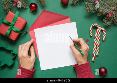 Weihnachten leer Leer für Brief an Santa oder Ihre Wunschliste oder advent Aktivitäten auf Grün. Weibliche Hand schreiben. Ansicht von oben mit der Kopie. Stockfoto