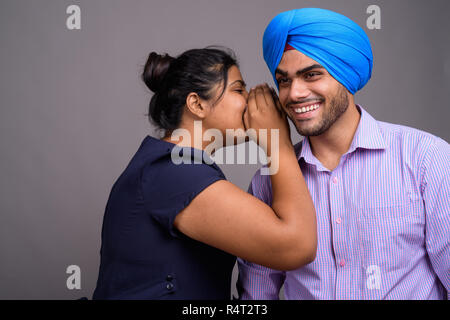 Junge glücklich indische Frau flüstert ihr lächelnd Freund Stockfoto