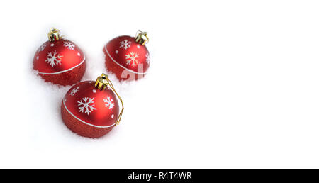 Gruß an Weihnachten Postkarte mit drei roten Weihnachten Spielzeug Bälle mit gemalten Schneeflocken im weichen Schnee liegen. Foto isoliert auf weißem closeu Stockfoto