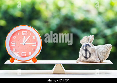 Geld und Zeit, Geld wechseln in Bargeld oder rückwärts Konzept: US Dollar im Sack, Tasche, Uhr auf Skalen auf Holztisch mit Natur Hintergrund. Stockfoto