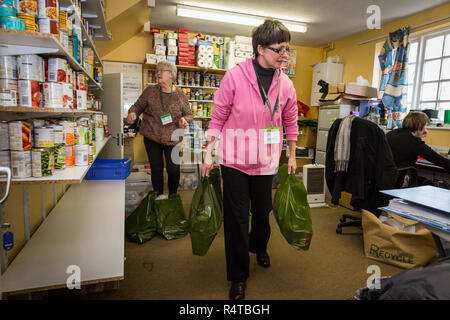 Food Bank Chichester freiwilligen Helfer stellt die Bedürftigen, Armen Menschen mit gespendeten Lebensmitteln in der Familie Kirche und Sortieren und das Essen in Ihrer Nahrung Depot lagern. Stockfoto