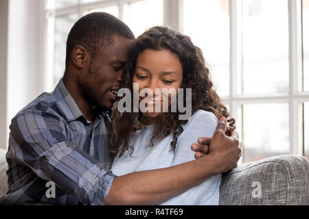 Liebevolle afrikanische amerikanische Mann umarmt Frau nach Streit Stockfoto