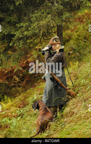 Die Jagd in den österreichischen Alpen: eine seltene Frau Jäger mit ihrem Hund Stockfoto