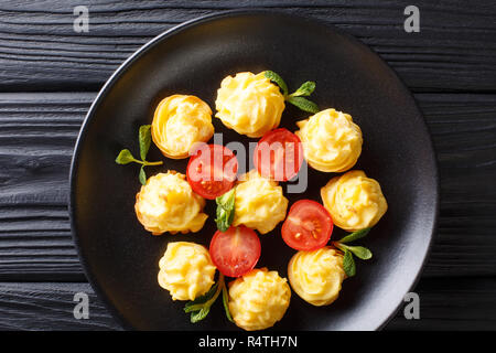 Festliche französische Vorspeise Herzogin Kartoffeln close-up auf einer schwarzen Platte auf einem Holztisch. horizontal oben Ansicht von oben Stockfoto