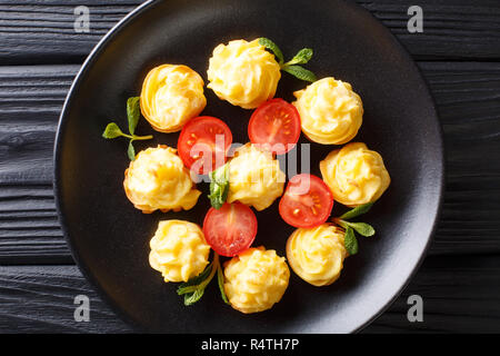 Herzogin Kartoffeln serviert mit Minze und Tomaten auf einer schwarzen Platte closeup. horizontal oben Ansicht von oben Stockfoto