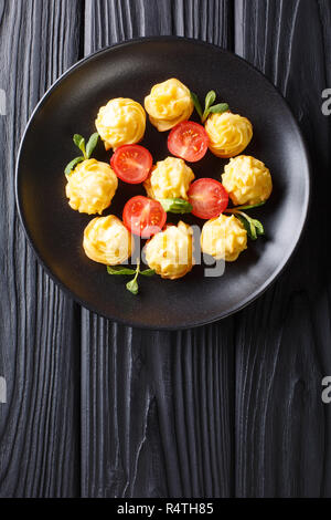 Appetitliche Snacks Herzogin Kartoffeln closeup auf eine schwarze Platte auf einem Holztisch. Vertikal oben Ansicht von oben Stockfoto