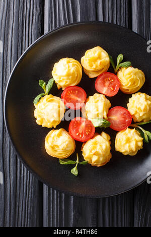 Festliche französische Vorspeise Herzogin Kartoffeln close-up auf einer schwarzen Platte auf einem Holztisch. Vertikal oben Ansicht von oben Stockfoto