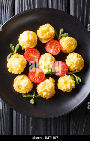 Herzogin Kartoffeln serviert mit Minze und Tomaten closeup auf eine schwarze Platte. Vertikal oben Ansicht von oben Stockfoto