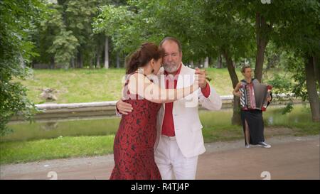 Positiven erwachsenen Freunde Tanzpaar Tanz im Garten. ältere Paare Tango tanzen. Älterer Mann und Frau tanzen libertango. Stockfoto
