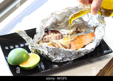 Rührschüssel Kabeljaufilet mit Pilz in Folie zum Grillen auf schwarze Platte mit Zitrone Stockfoto