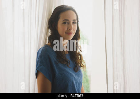 Porträt Lächeln, selbstbewusste Frau am Fenster Stockfoto