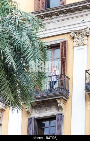 Barcelona, Spanien - 4. Oktober 2017: Frau auf einem Balkon auf dem Mobiltelefon stand in Placa Reial von La Rambla. Das Quadrat ist beliebt für Ess- und n Stockfoto