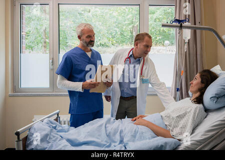 Ärzte runden machen, im Gespräch mit Patient im Krankenhaus Zimmer Stockfoto