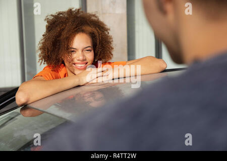 Junge Frau lächelnd und sprechen über Auto Mann Stockfoto