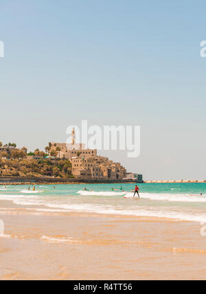 Surfer am Strand, Alma Strand entfernt, hinter der Altstadt von Jaffa mit der Kirche St. Peter, den alten Hafen, Tel Aviv-Jaffa, Israel Stockfoto