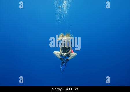 Weibliche Taucher hing in einer Lotus Pose für ein Sicherheits-Stop im blauen Wasser, Indischer Ozean, Malediven Stockfoto