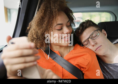 Junges Paar schlafen und Musik hören im Auto. Stockfoto