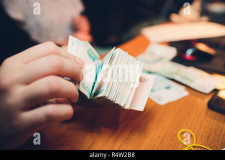 Männliche Hand hält einen dicken Stapel von Bargeld. Millionen russischer Rubel. Das Konzept der Reich, Reichtum, Gewinne, Business und Finanzen. Fünf tausendstel Rechnungen Banknoten. Eine lose Bündel von Geld. Stockfoto