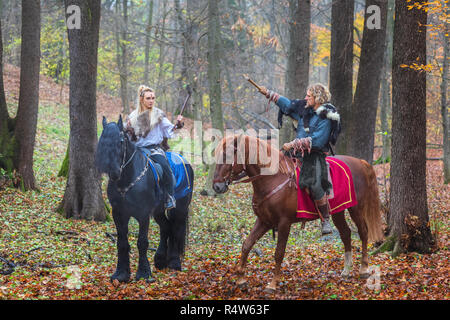 2 (2) Gefährliche skandinavischen Viking Krieger reiten Pferde und die Achsen über dem Kopf im Wald. Northern Krieger Wikinger bereit zu Raid Stockfoto