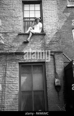 Junge Frau auf tenement Fensterbank in der Bronx, New York USA 1945 Sitzung Stockfoto