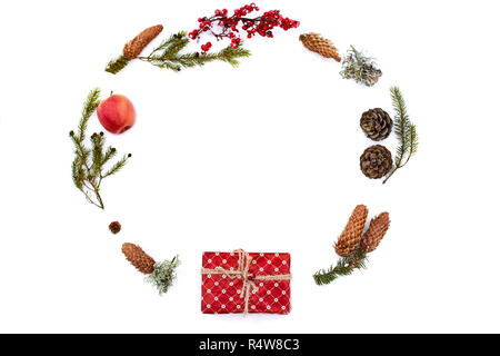 Weihnachten Zusammensetzung auf isolierten weißen Hintergrund. Neues Jahr wickelte Geschenk, Tannenzapfen, thuja oder Tannenzweigen, Apple und roten Beeren auf Schnee. Ansicht von oben, flach, kopieren. Kreis- oder abgerundete Form. Stockfoto