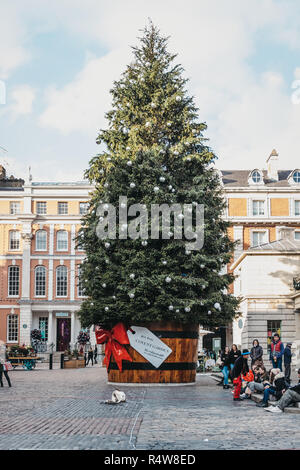 London, UK, November 21, 2018: riesige Weihnachtsbaum in einem Topf mit einem Geschenk tag vor Covent Garden Market, einer der beliebtesten touristischen Websites Stockfoto