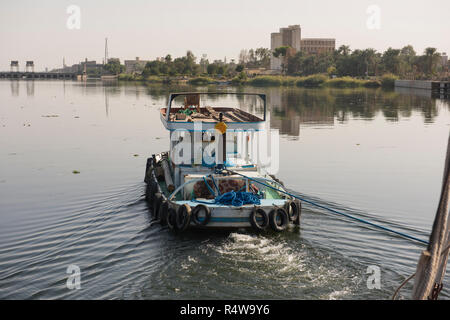 Kleine Schlepper abschleppen einer Yacht auf Nil in Ägypten durch ländliche Stadt Landschaft in Edfu Stockfoto