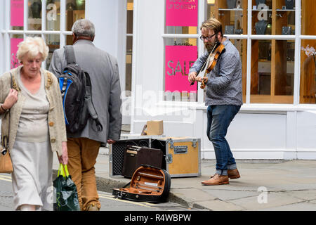 Menschen gehen vorbei, ohne männlichen Gaukler (man Straßenmusik) stehend, Durchführung und Spielen der Violine auf City Centre Street - York, North Yorkshire, England, UK. Stockfoto