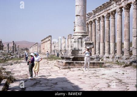 Szene von westlichen Touristen fotografieren die Ruinen der großen Kolonnade Cardo Maximus bei Apamea, Syrien, Juni 1994. Am mittleren Rahmen ist die Basis für eine Spalte in der Mitte der Straße. () Stockfoto