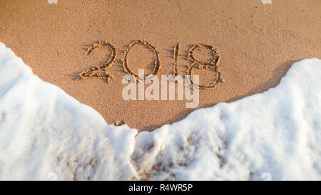 Closeup Bild der Wellen des Ozeans über 2018 Nummern auf nassem Sand geschrieben. Konzept der Feiern und Reisen auf Winterurlaub. Stockfoto