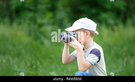 Kleine lustige junge Praktizierende bei der Fotografie im Freien Stockfoto