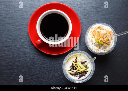 Rot Tasse Kaffee mit Take away Desserts auf schwarzem Schiefer Hintergrund Stockfoto