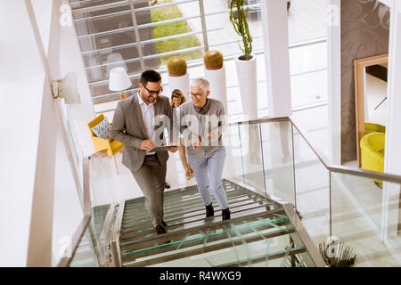Gruppe der Unternehmer und Unternehmerinnen zu Fuß und unter Treppen in einem Bürogebäude Stockfoto