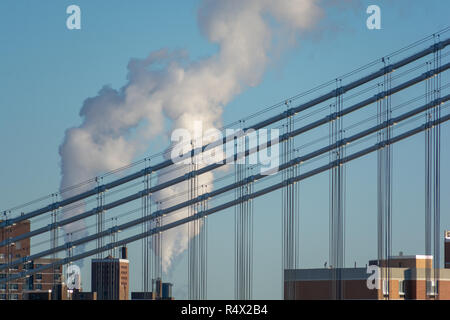 Detail der Kabel auf der Manhattan Bridge mit rauchenden Schornstein hinter von der Brooklyn Bridge an einem klaren Wintertag genommen Stockfoto