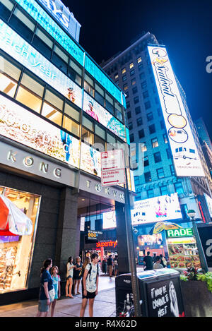 New York City, USA - 30. Juli 2018: die Geschäfte in der Nacht auf der Seventh Avenue (7. Avenue) Neben der Times Square mit Menschen um und große Werbung Bildschirm Stockfoto