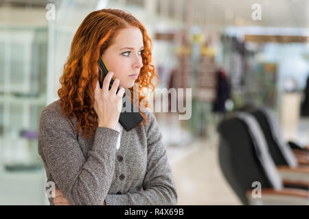 Rothaarige Mädchen sprechen per Telefon. Selektiver Fokus mit geringer Tiefenschärfe. Stockfoto