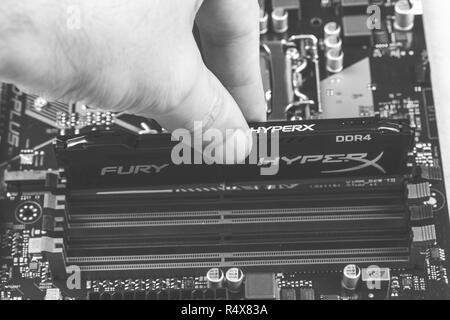 Maykop, Russland - November 9, 2018: Man installiert ein DDR4 DIMM 16 Gb Kingston HyperX Fury Speicher RAM-Modul in den Steckplatz auf dem Motherboard, Nahaufnahme, bla Stockfoto