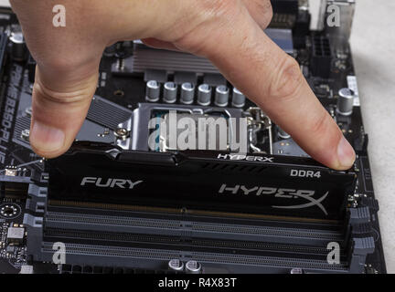 Maykop, Russland - November 9, 2018: Man installiert ein DDR4 DIMM 16 Gb Kingston HyperX Fury Speicher RAM-Modul in den Steckplatz auf dem Motherboard closeup Stockfoto