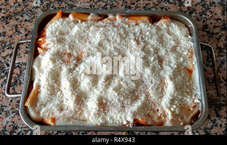 Ein Backblech mit einigen raw-Lasagne mit Tomatensauce und geriebenem Parmesan bereit in einem Ofen gekocht zu werden Stockfoto