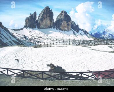 Herrlicher Blick von der Terrasse auf das Symbol der Dolomiten - Drei Zinnen. Blick von der Berghütte mit hohen felsigen Grat in Wolken im Hintergrund. Stockfoto