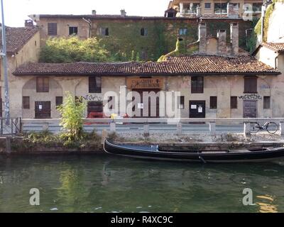 Eine Landschaft von der Navigli künstliche Kanal mit einer Gondel stil Boot, vor dem typischen ländlichen Haus mit Efeu in Mailand, Lombardei, Italien Stockfoto