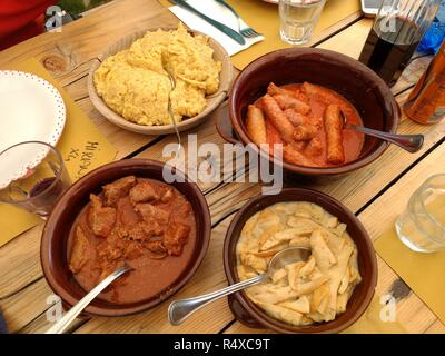 Traditionelle hausgemachte italienische Gerichte, darunter Polenta (gekochtes Maismehl) neben Würstchen, Fleisch und Pilzen Eintopf in Gewürzen und Tomatensauce. Stockfoto