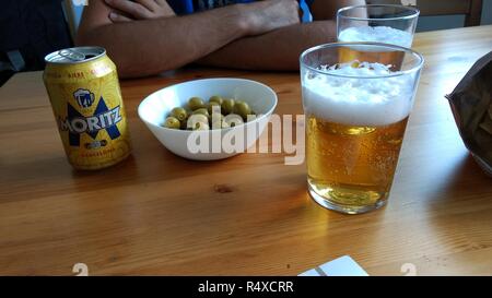 Eine Farbtabelle mit ein typisch Spanisches Bier kann, eine Schale mit einigen grünen Oliven und zwei Gläser Lagerbier in einer Bar Stockfoto