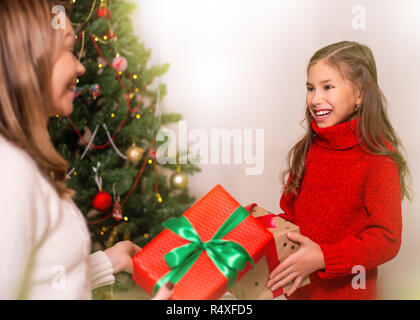 Fröhliche Mamma und ihre süße Tochter Mädchen den Austausch von Geschenken. Frohe Weihnachten und schöne Feiertage. Stockfoto