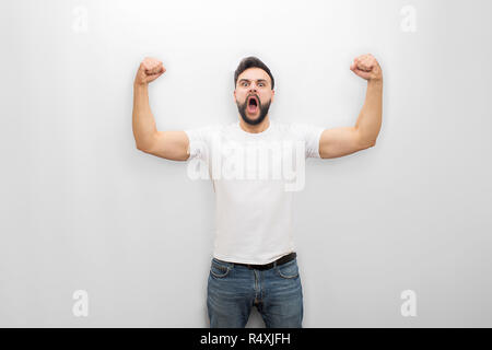 Junger Mann, Schreien und Kreischen, während posieren. Er ist stark. Kerl zeigt seine Muskeln. Auf weissem Hintergrund. Stockfoto