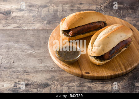 Choripan. Traditionelle Argentinien Sandwich mit Chorizo und chimichurri Sauce auf hölzernen Tisch Stockfoto